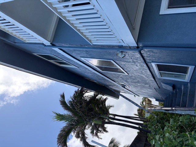 Two-story residence with finished exterior trim under palms