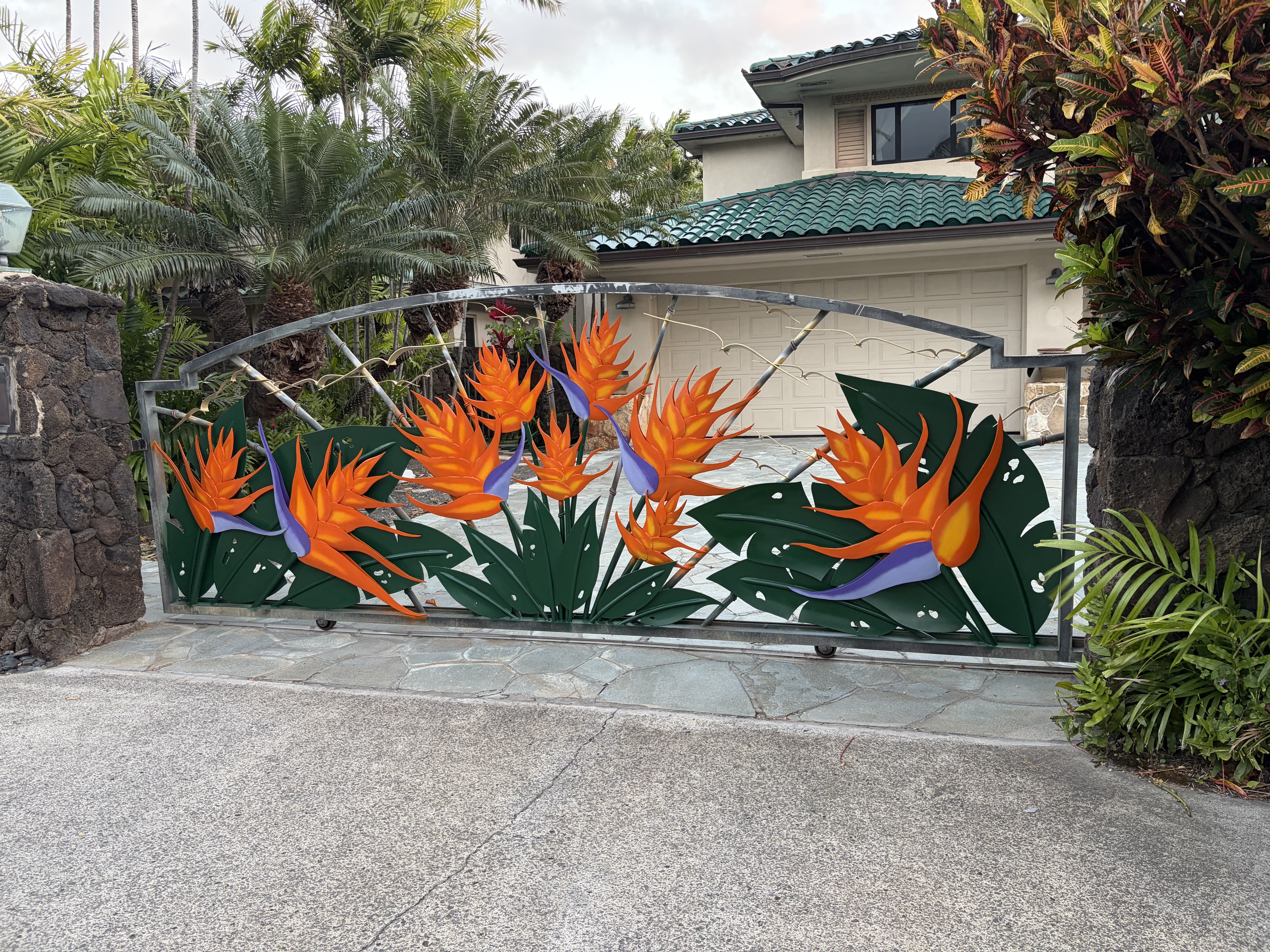 The same gate hand-painted with bright orange birds of paradise, gold and purple detailing, lush green leaves, finished by Rob the Painter