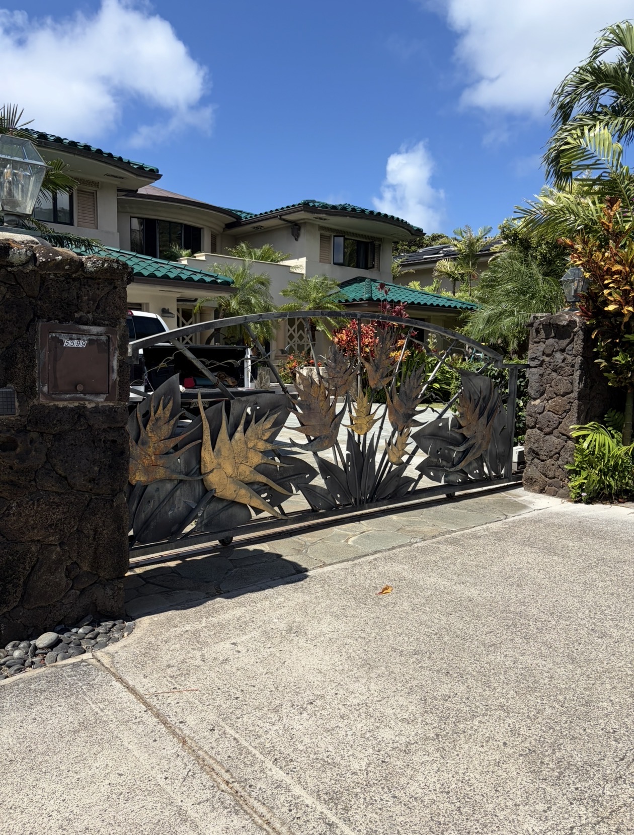 The driveway gate as originally installed with raised silhouettes of ginger flowers in plain steel, no color, palms in the background